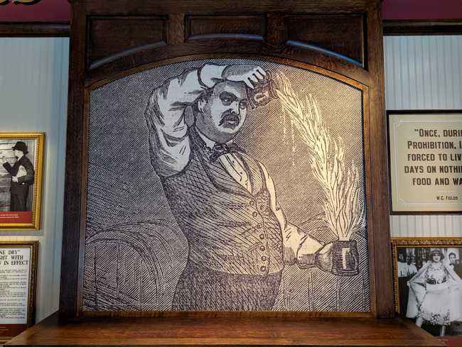 An enlarged print of an old-time-y bartender pouring a flaming drink.