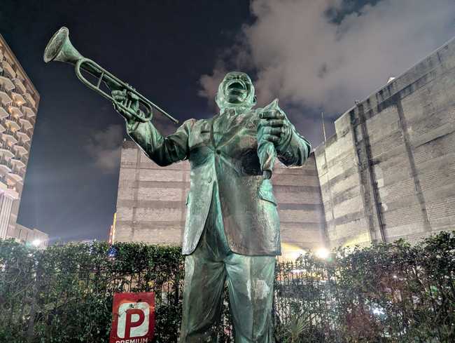 A statue of Louis Armstrong, holding a trumpet and laughing.