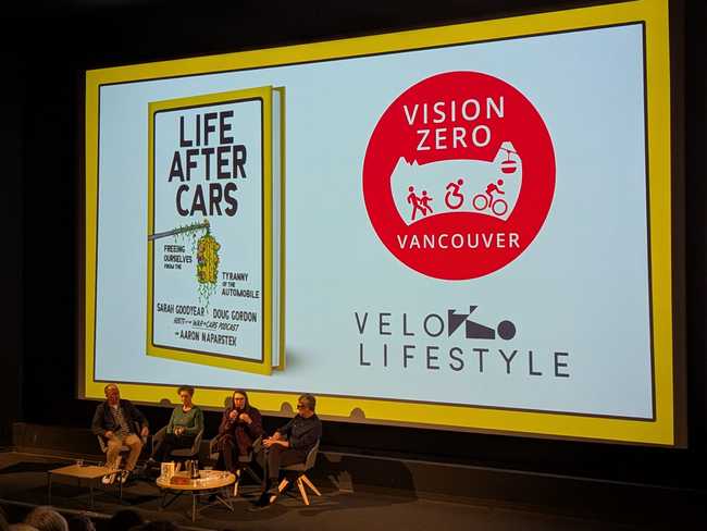 The same four people are still in front of the screen. On the left, the screen is showing the book again. On the
right, it's showing the logos for Vision Zero Vancouver and Velo Lifestyle.