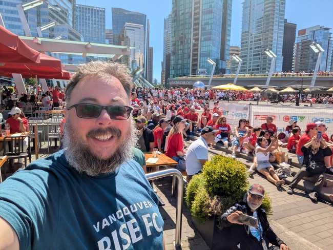 Me in front of a crowd of people in a public plaza. You can see a bit of Vancouver's Olympic Cauldron in the back.