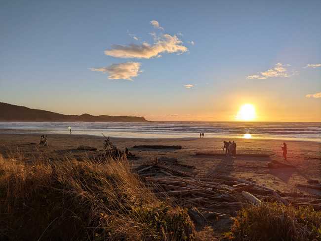 The sun setting over the water, with beach and grasses in the
foreground.