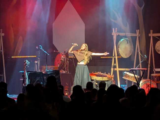 The same woman, but now centre stage and singing into a microphone.