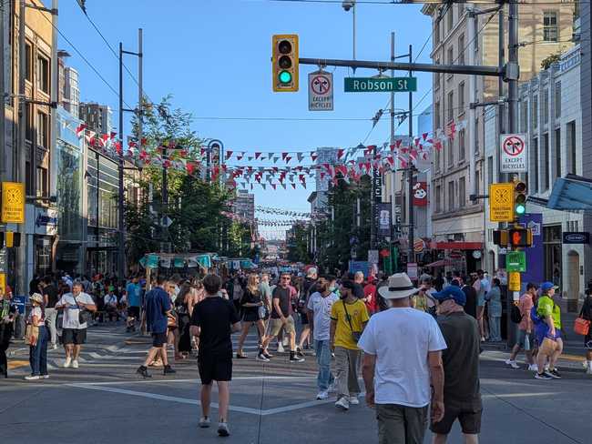 Looking down Granville St. It's filled with people. Bunting crisscrosses overhead.