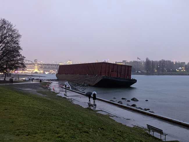 A large barge stuck on rocks by a footpath.