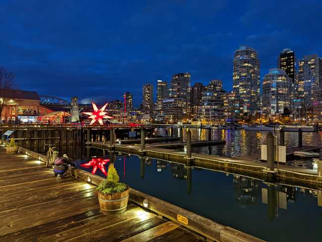 Docks along False Creek at night, with skyscrapers in the background.