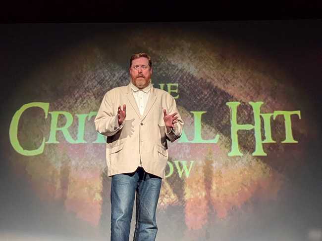 A man in an extra-large suit jacket on stage.