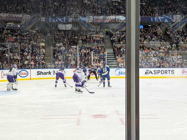 The referee is about to drop the puck as the players wait in anticipation.
