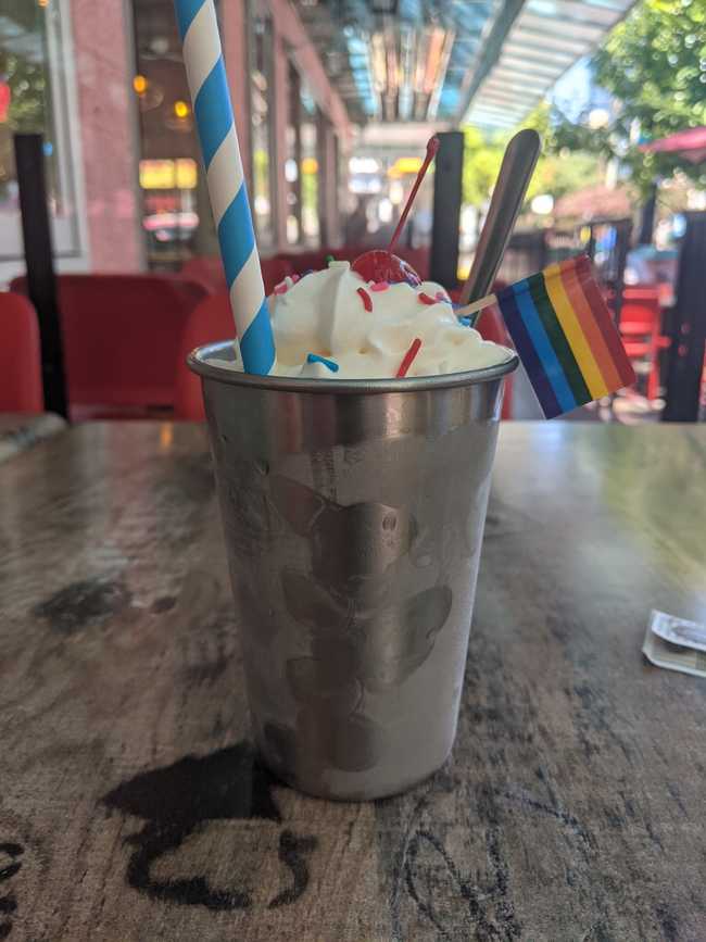 A milkshake on a patio with a little pride flag.