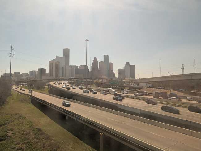 A massive stretch of freeways heading towards a cluster of skyscrapers.