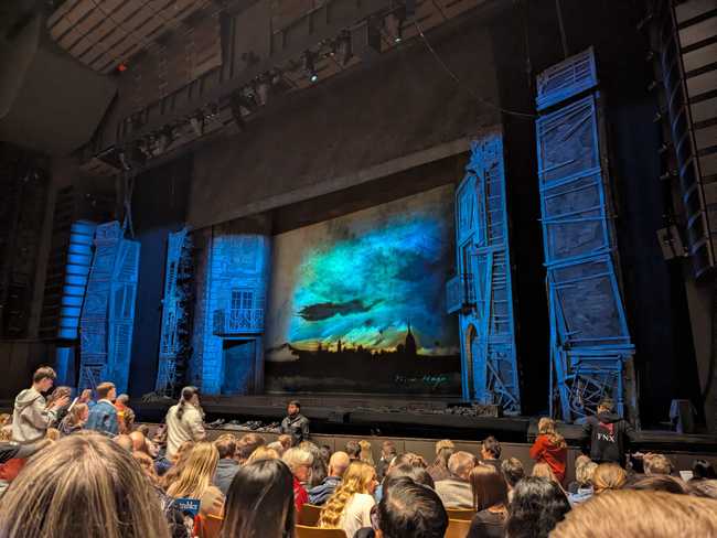 The empty stage before the show. On the sides are building facades, and the back of the stage shows a smokey
cityscape.