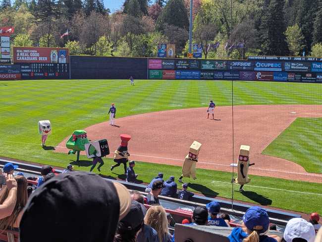 A group of people in sushi costumes racing from 3rd base to home.
