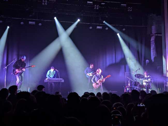 Concert picture, but of a different band. There are five people on stage: five dudes, and a woman at the
front.