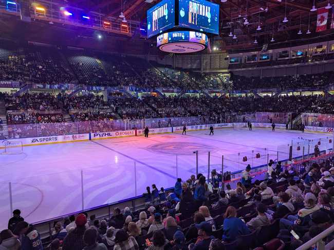 The lights have been darkened to purples and pinks. A crew of people are on the ice, sweeping up ice shavings.