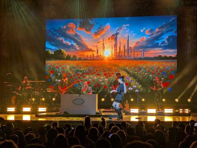 Now the backdrop is showing a fantasy city in the distance and a field of flowers. Up front, a woman in profile is
dancing on stage.