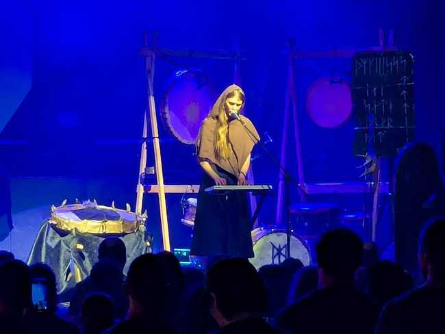 A woman on stage playing synthesizer.