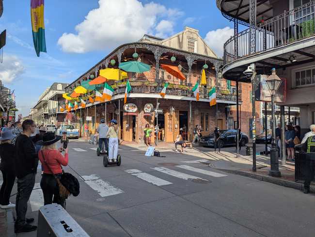 A busy street. More people on segways, bars, and some street dancers.